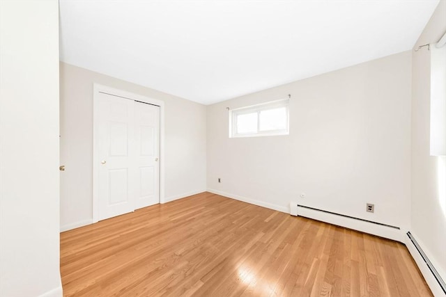 unfurnished bedroom with a baseboard radiator and light hardwood / wood-style floors