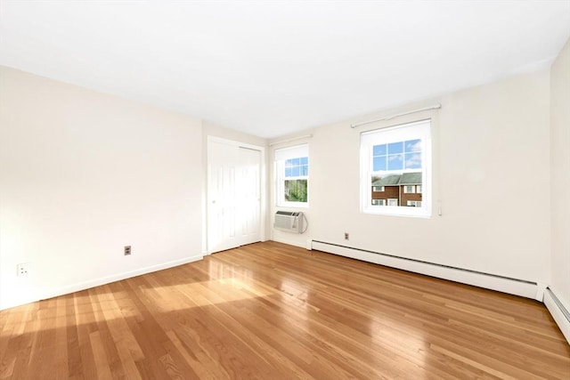 empty room with wood-type flooring, a baseboard heating unit, and a wall unit AC