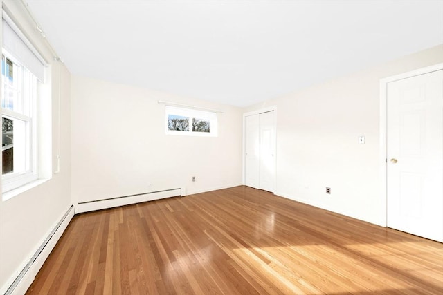 empty room with wood-type flooring and baseboard heating