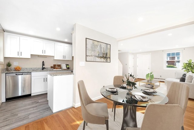 dining area featuring sink, a baseboard radiator, and light hardwood / wood-style floors