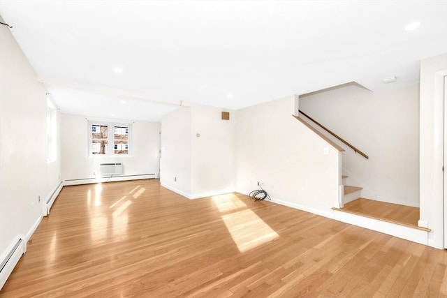 unfurnished living room featuring a baseboard radiator, a wall unit AC, and light hardwood / wood-style flooring