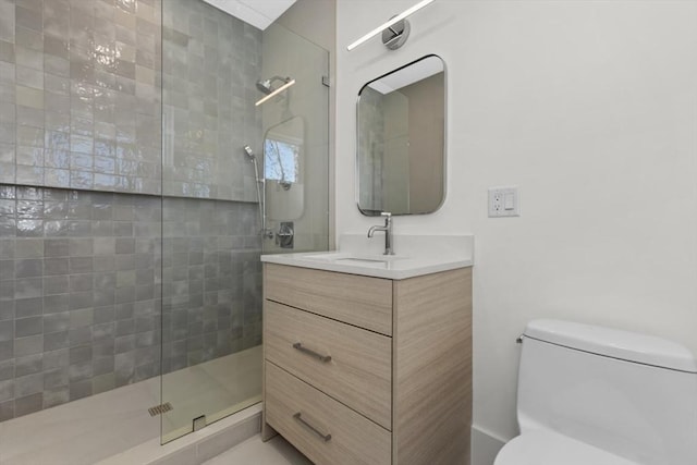 bathroom featuring vanity, toilet, and a tile shower