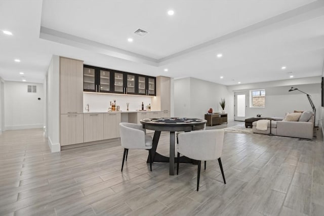 dining area featuring a raised ceiling and bar area