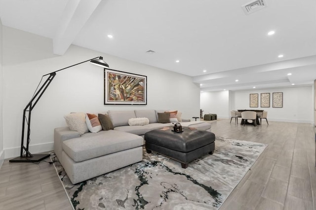 living room featuring beam ceiling and light hardwood / wood-style flooring