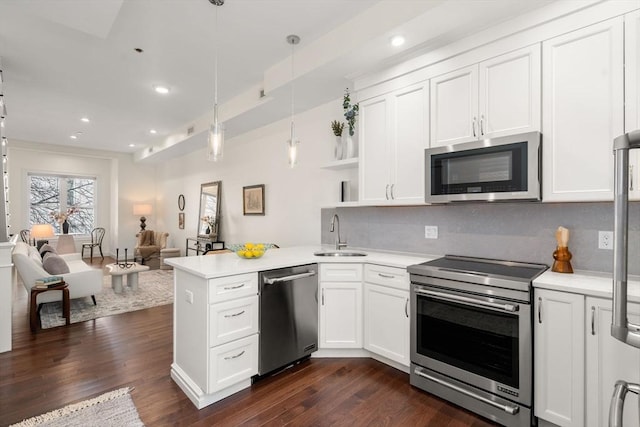 kitchen featuring a peninsula, a sink, stainless steel appliances, light countertops, and open floor plan