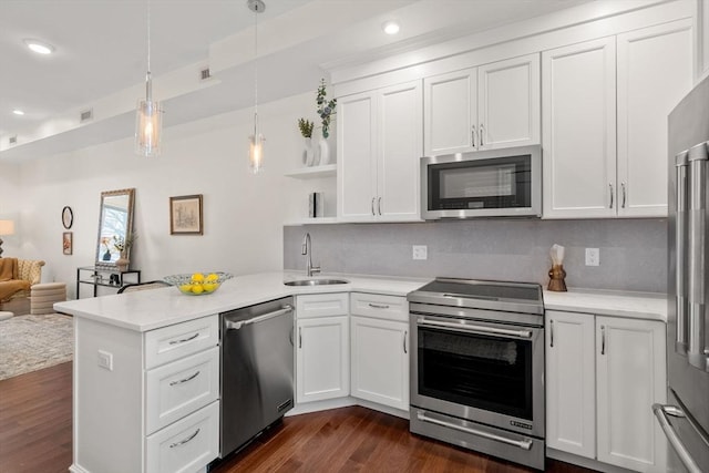 kitchen with dark wood-type flooring, open floor plan, appliances with stainless steel finishes, a peninsula, and a sink