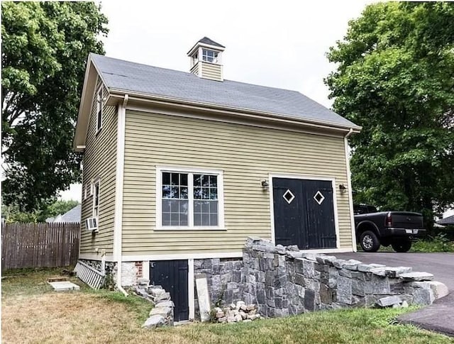 view of front facade featuring a garage, aphalt driveway, fence, and cooling unit