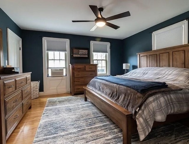 bedroom with a ceiling fan, cooling unit, and light wood-type flooring