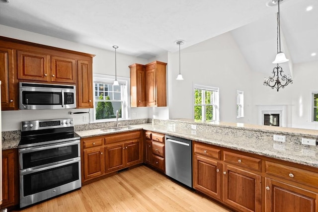 46 Walden Way Unit 46, Milford, MA 01757 - kitchen featuring appliances with stainless steel finishes, a sink, light wood-type flooring, brown cabinets, and light stone counters