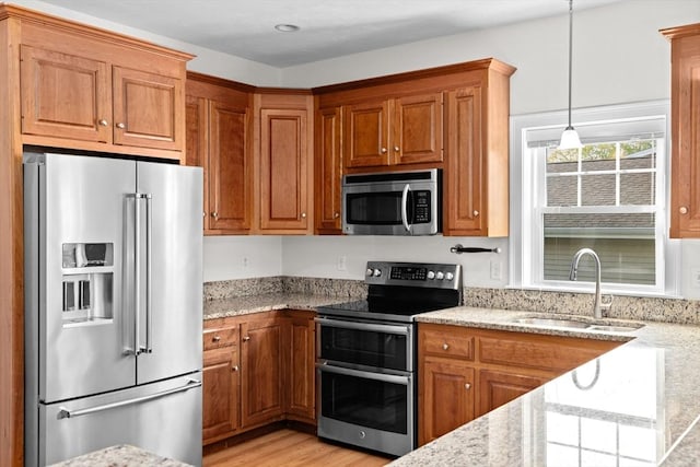 46 Walden Way Unit 46, Milford, MA 01757 - kitchen with stainless steel appliances, a sink, brown cabinetry, and light stone countertops