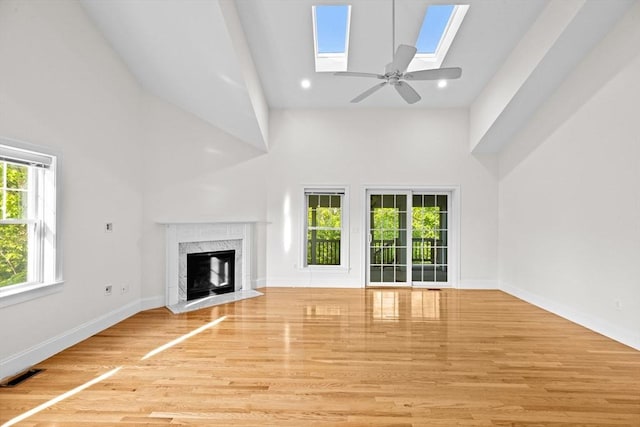 46 Walden Way Unit 46, Milford, MA 01757 - unfurnished living room with a high ceiling, plenty of natural light, a skylight, wood finished floors, and a high end fireplace
