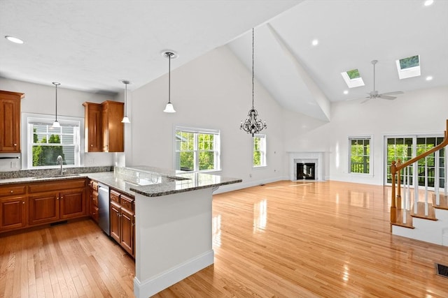 46 Walden Way Unit 46, Milford, MA 01757 - kitchen with dishwasher, high vaulted ceiling, a sink, a glass covered fireplace, and light wood-style floors