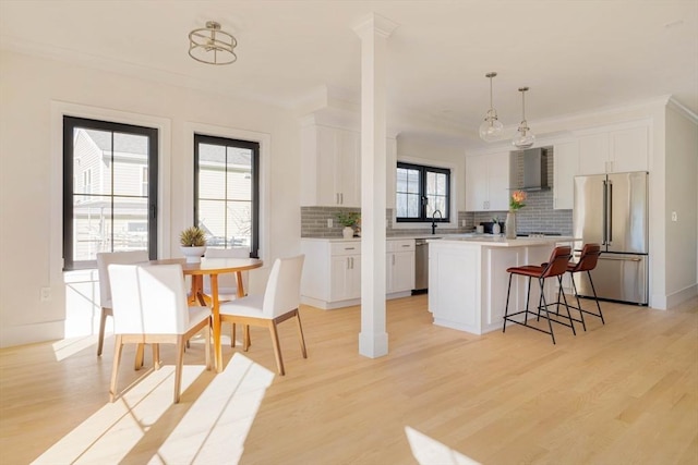 kitchen with stainless steel appliances, white cabinetry, hanging light fixtures, and a kitchen island