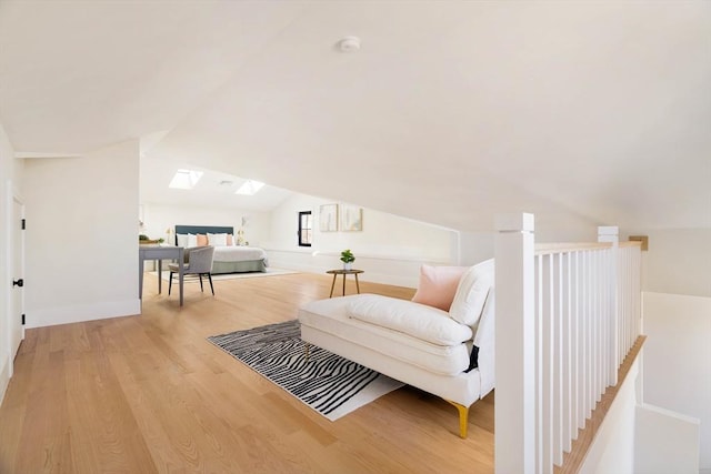 sitting room featuring light wood-type flooring and lofted ceiling with skylight