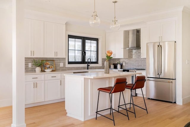 kitchen with white cabinets, a center island, wall chimney exhaust hood, and high end fridge