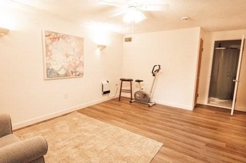 unfurnished room with wood finished floors, a ceiling fan, and baseboards