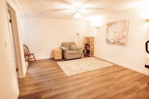 sitting room with wood finished floors, ceiling fan, and baseboards