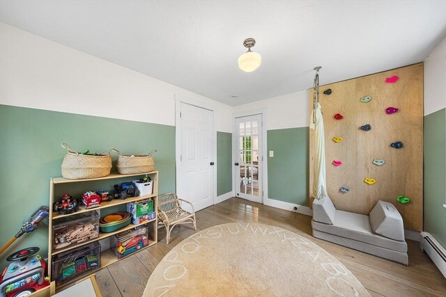 game room with baseboard heating, wood finished floors, and baseboards