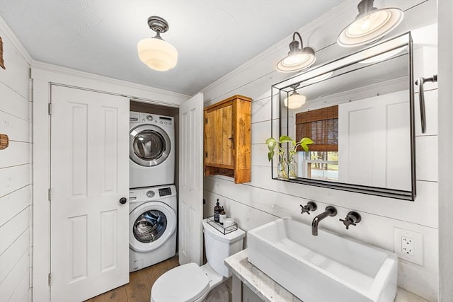 bathroom with stacked washer / dryer, ornamental molding, wood finished floors, toilet, and vanity