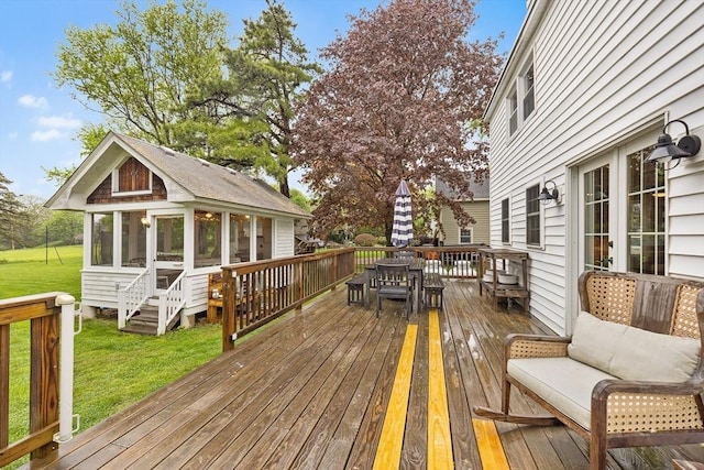wooden deck with a sunroom, outdoor dining space, and a yard