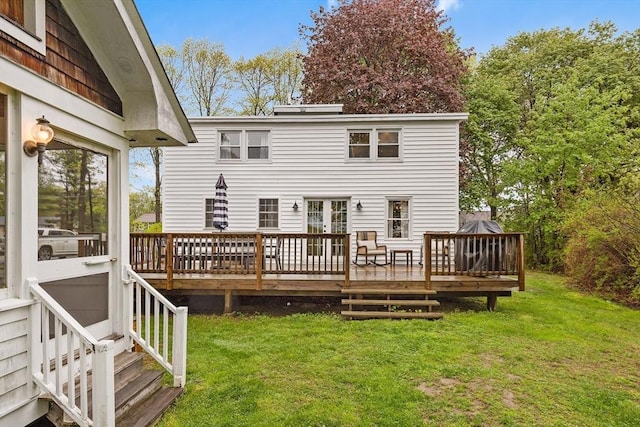 rear view of house featuring a wooden deck and a lawn