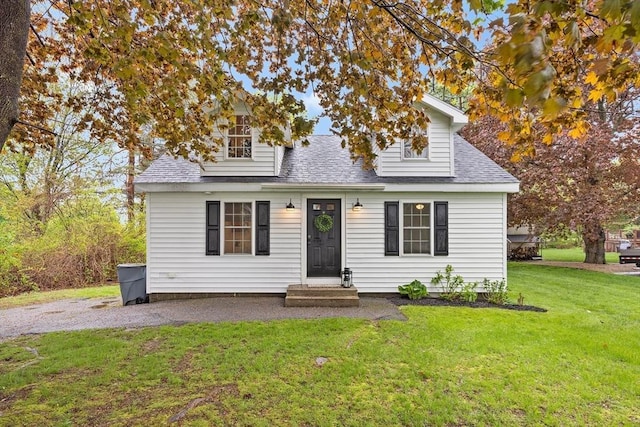 view of front facade with roof with shingles and a front lawn