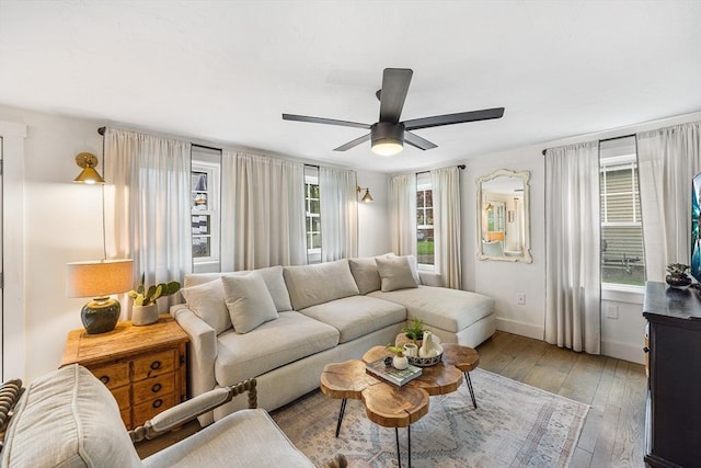living area featuring ceiling fan, hardwood / wood-style floors, and baseboards