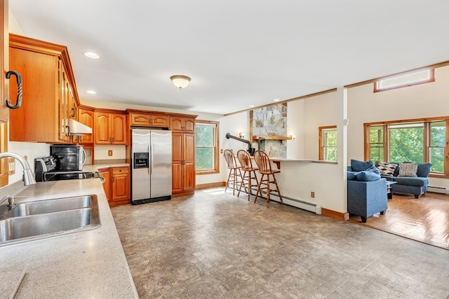 kitchen with a baseboard radiator, stainless steel refrigerator with ice dispenser, sink, and a healthy amount of sunlight