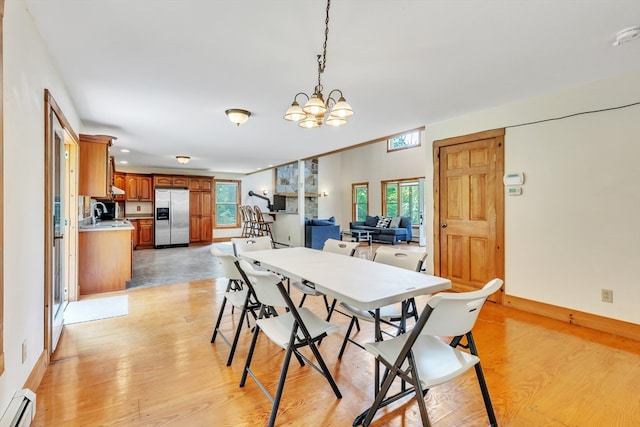 dining area featuring sink, an inviting chandelier, light hardwood / wood-style flooring, and baseboard heating