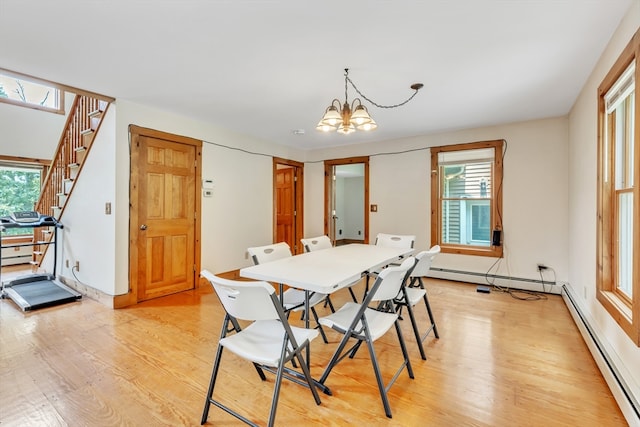 dining area with an inviting chandelier, a baseboard heating unit, and light wood-type flooring