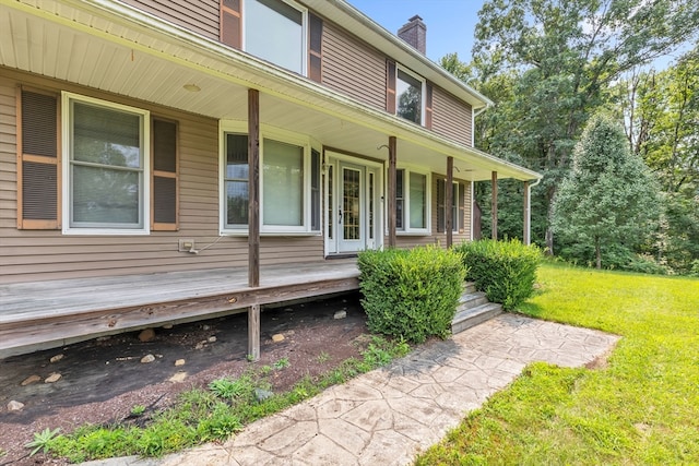 property entrance featuring covered porch and a yard