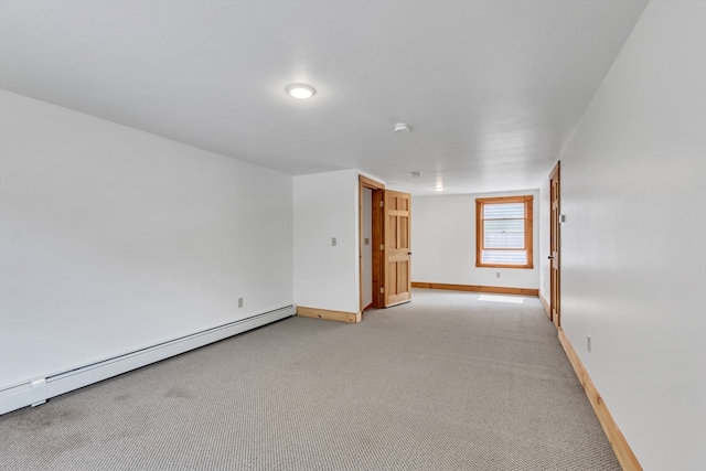 carpeted spare room with a baseboard heating unit