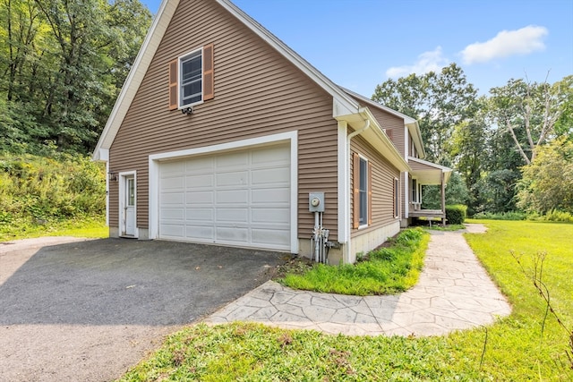 view of side of property featuring a garage and a lawn