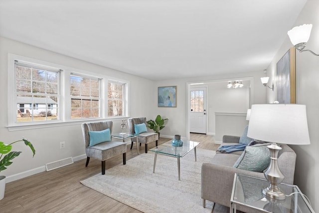 living area with visible vents, baseboards, a healthy amount of sunlight, and wood finished floors