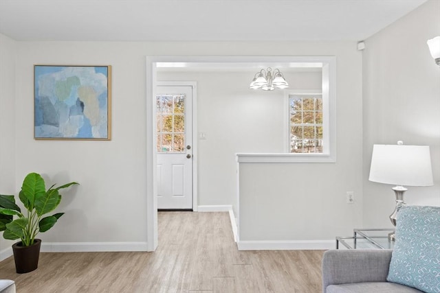 living area with wood finished floors, a notable chandelier, a healthy amount of sunlight, and baseboards