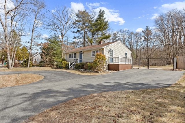 view of home's exterior featuring a chimney, driveway, and fence