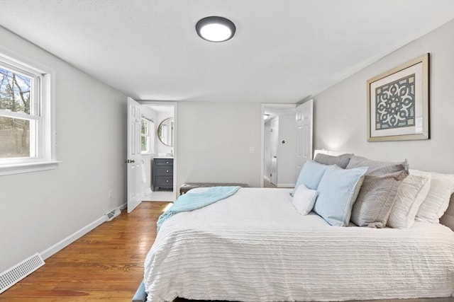 bedroom featuring visible vents, baseboards, and wood finished floors