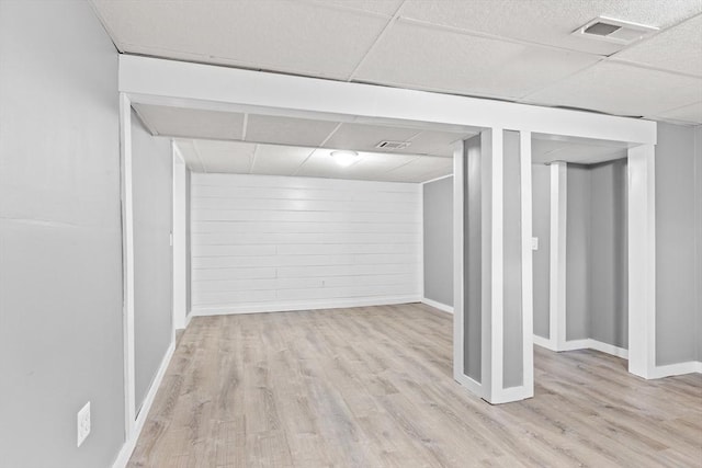 finished basement featuring a paneled ceiling, visible vents, baseboards, and wood finished floors