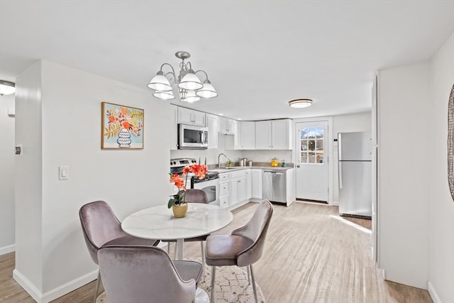 dining room featuring light wood-style flooring, an inviting chandelier, and baseboards