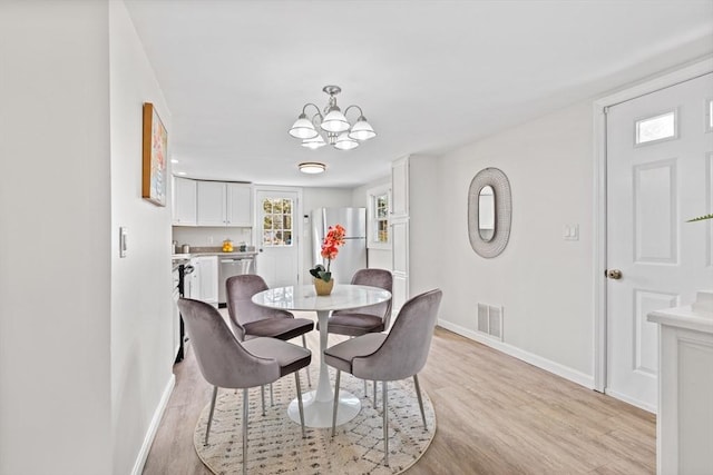 dining area featuring a notable chandelier, baseboards, visible vents, and light wood finished floors