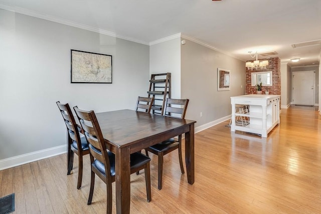 dining area featuring light wood-type flooring, crown molding, and an inviting chandelier