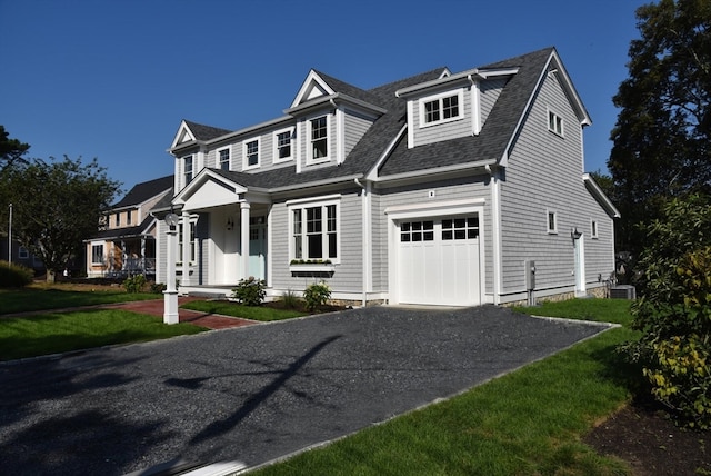 view of front of home featuring a front lawn, central AC unit, and a garage