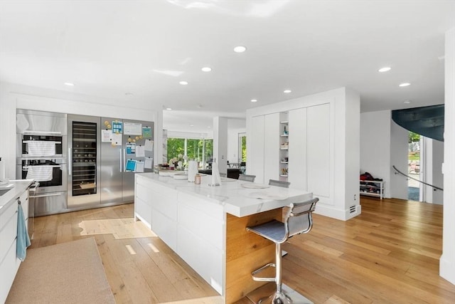 30 Whipple Rd, Lexington, MA 02420 - kitchen with light wood-type flooring, recessed lighting, white cabinets, a large island, and light stone countertops