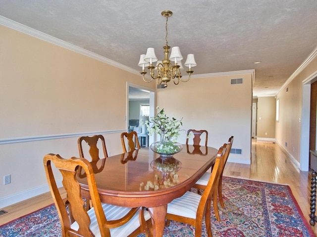 dining room featuring crown molding, light hardwood / wood-style flooring, and an inviting chandelier