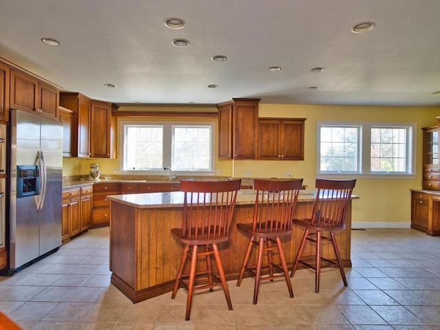 kitchen featuring plenty of natural light, a center island, stainless steel fridge with ice dispenser, and a breakfast bar area