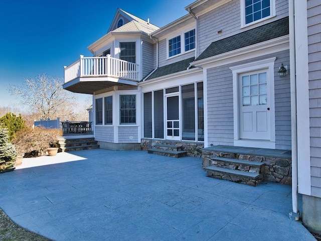 rear view of property with a patio, a balcony, and a sunroom