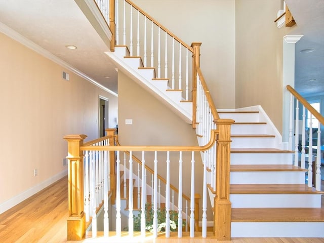 stairs featuring hardwood / wood-style floors and crown molding