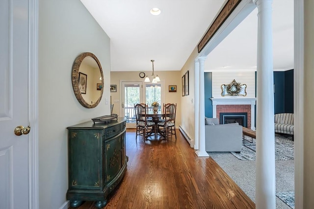 interior space with baseboard heating, baseboards, dark wood-type flooring, and ornate columns