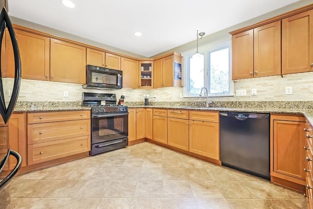 kitchen featuring black appliances, light stone countertops, backsplash, and a sink