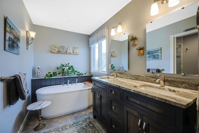 bathroom with a sink, a freestanding bath, and double vanity